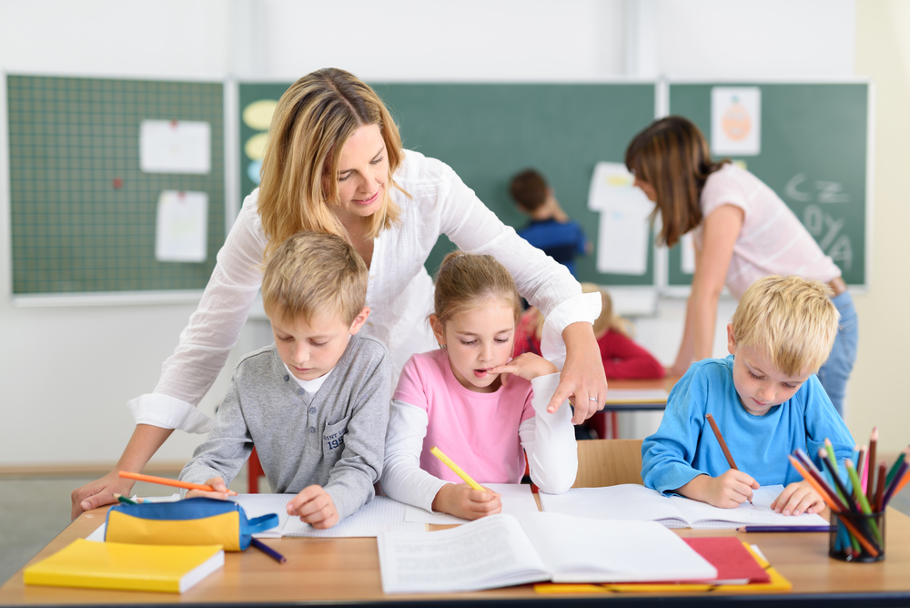 female teaching assistant helping students in class