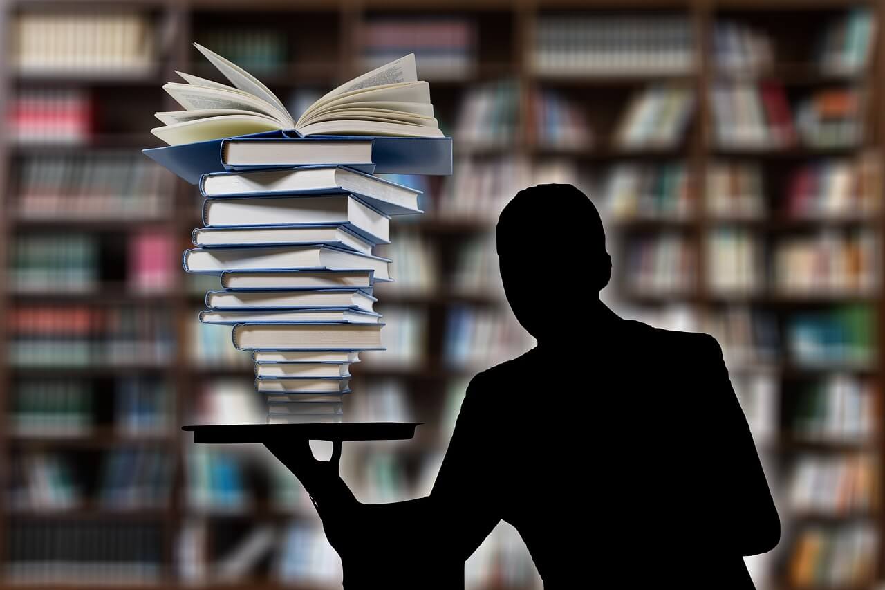 Man holding a tray under a pile of books in a library