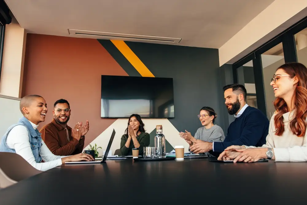 Example of emotional intelligence in the workplace - business people applauding their colleague in a boardroom